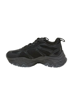 Baskets de sport noires avec semelle épaisse ondulée, dessus en mesh et synthétique, lacets à l'avant et languette de tirage sur le col rembourré du talon.