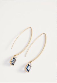 Duge zlatne naušnice s zakrivljenim kukicama i pravokutnim tamnoplavim dragim kamenjem postavljenim u zlato na krajevima.