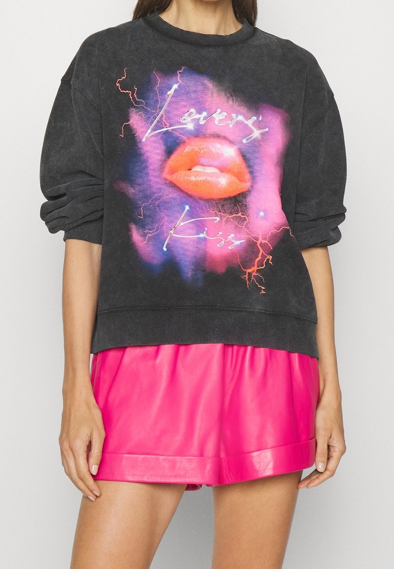 Sudadera gris oscuro con un gráfico de labios rojos y el texto "Lovers Kiss", con acentos en neón rosa y azul. Puños y cuello acanalados.