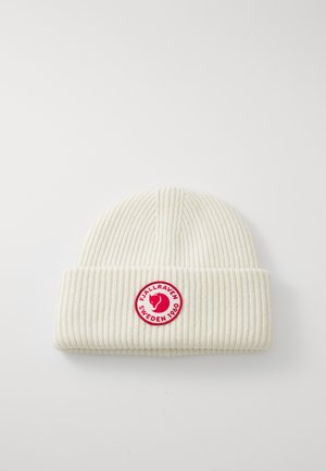 Cream-colored ribbed knit beanie with folded cuff featuring a round red logo patch reading "Fjällräven Sweden 1960".
