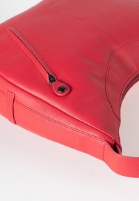 Rode leren tas met een soepele textuur, voorzien van een ritsvak en een stevige schouderband. Het ontwerp is elegant met minimale naden.