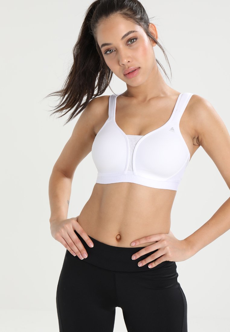 Sujetador deportivo blanco hecho de una tela suave, con tirantes anchos, forma redondeada y parte frontal sin costuras. Apto para ropa deportiva.