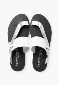 White and silver sandals with a flat black sole, featuring a wide front strap and a metallic crossover design at the toe. Brand logo visible.