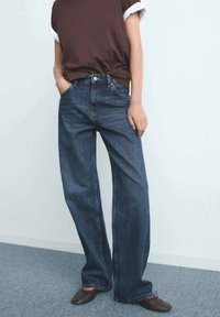 Donkerblauwe denim jeans met een losse pasvorm, voorzien van een klassiek vijf-pocket ontwerp en een metalen knoopsluiting. Casual bruin topje, eenvoudige stijl.