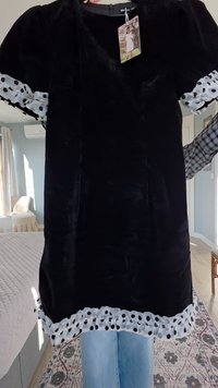 Black velvet dress with puff sleeves, featuring white polka dot lace trim at the hem. Tag attached at the neckline.