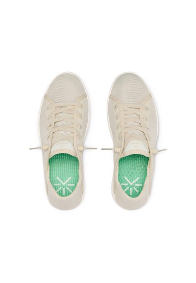 Beige sneakers met een gestructureerde mesh bovenkant, vetersluiting en groene gestreepte binnenzolen met een logo.