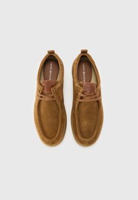 Chaussures en daim marron avec un bout rond et une semelle en caoutchouc. Dotées d'accents en cuir et de détails brodés. Logo embossé sur la languette.