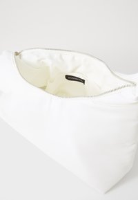 White fabric clutch bag with a smooth exterior, zip closure, and soft interior lining. Features a label inside. Compact and simple design.