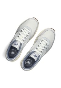 Zapatillas deportivas de color gris claro con cordones blancos, parte superior sintética, acentos azules y suela de goma color crema. Presenta un logo en la plantilla.