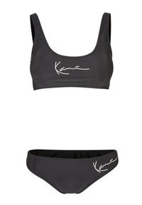Set di bikini nero con un design sportivo. La parte superiore presenta spalline larghe e una stampa del logo bianco. La parte inferiore ha un taglio classico con un accento del logo abbinato.