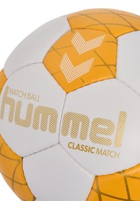 Hummel Classic Match fotboll med vita och orange paneler, texturerad yta och geometriskt gult mönster med varumärkeslogotyp.