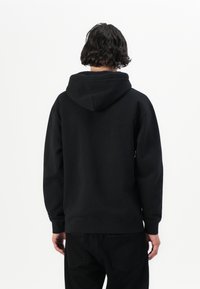 Black cotton hoodie with a drawstring hood, relaxed fit, ribbed cuffs, and hem. Back view showing soft texture and seam details.