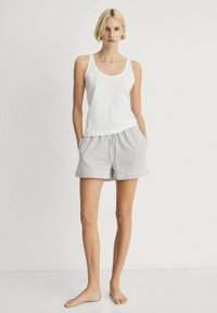 Hvid sansærmet tanktop parret med grå og hvide stribede shorts. Shortsene har en elastisk talje og sidelommer.