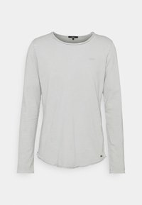 Helles graues Langarmshirt mit Rundhalsausschnitt, dezentem Markenlogo auf der Brust und einem kleinen Etikett nahe dem Saum.