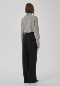 Pel�ēks, ribots augsta kakla džemperis apvienots ar augsta vidukļa, plati melniem bikses, kurās ir sānu kabatas un tīra, piegriezuma siluets.