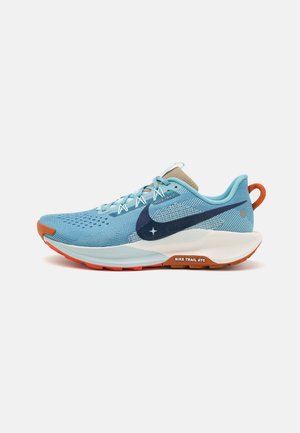 Vue de côté d’une chaussure de trail Nike bleue, avec un Swoosh foncé, une semelle intermédiaire blanche, une semelle extérieure orange et une bride au talon orange.