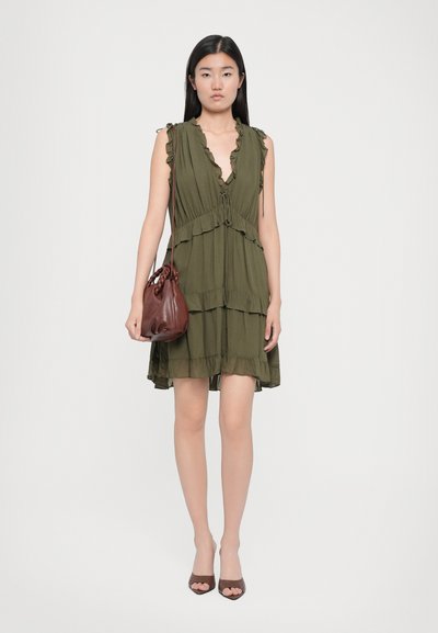 Olivovo zelené vrstvené šaty s volánikovými okrajmi a viazaním vpredu, kombinované s malou hnedou koženou kabelkou a hnedými sandálmi na opätku s otvorenou špičkou.