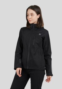 Veste noire imperméable avec fermeture éclair, col montant, deux poches latérales et un logo sur la poitrine. Texture lisse avec un design léger.