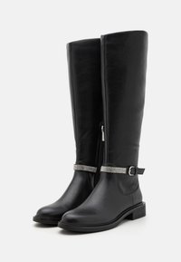 Bottes noires montantes jusqu'au genou en cuir lisse, dotées d'une fermeture éclair latérale, d'une sangle décorative ornée de strass, et d'un talon carré.