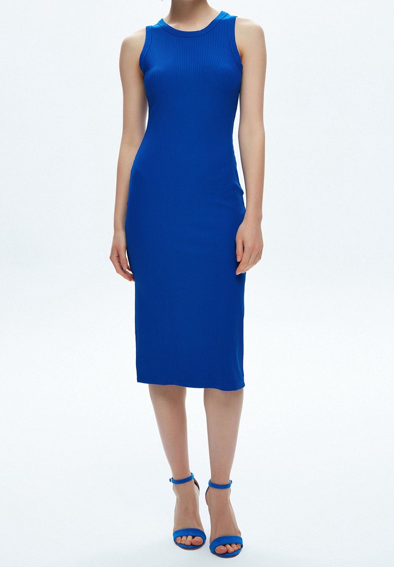 Kungsblå randig bodycon-klänning med rund hals och ärmlös design, matchad med strappy högklackade sandaler.