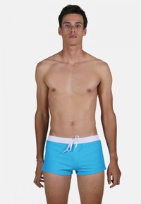 Shorts de bain turquoise avec une taille et un cordon de serrage blancs. Le tissu est lisse et le design est ajusté, atteignant le mi-thigh.