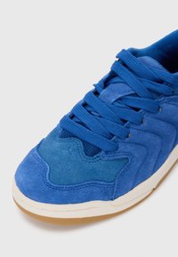 Baskets en daim bleu avec des superpositions texturées, des lacets doux et une semelle en caoutchouc gomme, dotées d'un col rembourré et d'accents en mesh pour un confort optimal.