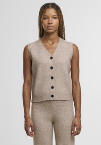 Svijetlosmeđi pleteni prsluk bez rukava s V-izrezom, s pet crnih gumba sprijeda i rebrastim rubom. Mekana, teksturirana tkanina.