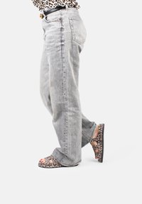 Gray denim straight-leg jeans paired with open-toe leopard print sandals. Sandals feature cutouts and a black sole.