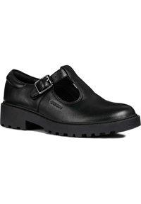 Zapatos negros de cuero con un diseño de tira en T y detalle de hebilla, que cuentan con una suela gruesa y texturizada para mayor agarre. Se puede ver la marca Geox.