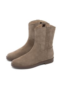Botas de tobillo de ante en color tostado con punta redonda, cremallera lateral yuna suela baja y plana en color marrón. Diseño minimalista y textura suave.