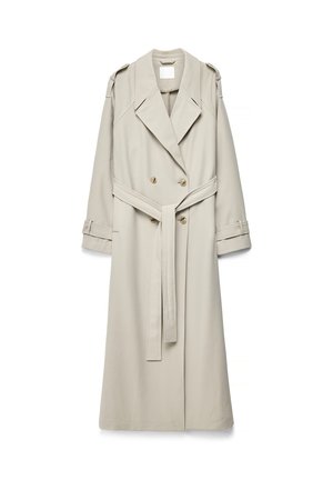 Bēša gara tranšejakas ar dubultām pogām, platām atlokām, jostu viduklī, plecu epoletem un aproču siksnām uz baltā fona.