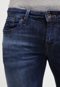 Mörkblå denimjeans med slim fit, med en klassisk femfickedesign, subtila blekningar och kontrasterande sömmar vid fickorna.