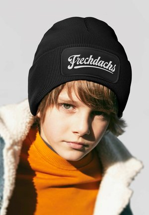 Black knit beanie with a textured surface and a prominent white logo patch reading "Frechdachs." Worn by a child with light brown hair.