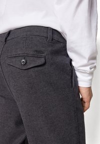Pantaloni di lana grigio scuro con motivo a zig zag, tasca posteriore con bottone e una piccola etichetta con logo in vita.