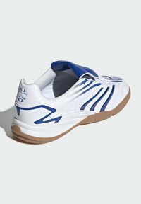 Scarpa sportiva bianca con accenti blu, superiore in materiale sintetico texturizzato, design curvo e suola in gomma naturale; presenta un collare slip-on.