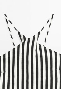 Black and white vertical striped sleeveless top with thin crossed shoulder straps on a white background.