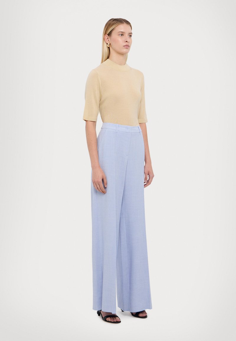 Beige gemêleerde top met korte mouwen, gecombineerd met lichtblauwe, wijde broek. De outfit heeft een gladde textuur en een op maat gesneden silhouet.