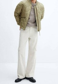 Gequiltede olijfgroene bomberjack, lichtgrijze gebreide trui, off-white cargobroek, zwarte enkellaarzen. Minimalistisch ontwerp met functionele zakken.