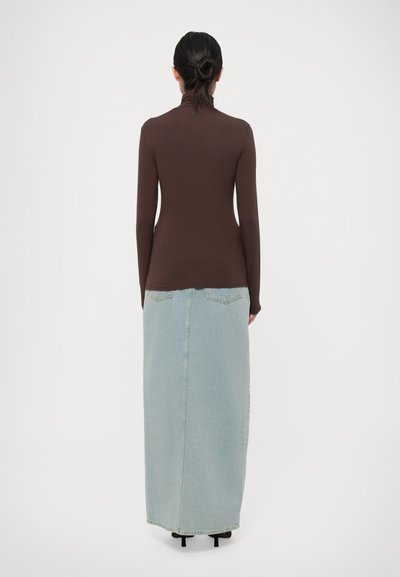 Brown long-sleeve top with a high neck, paired with a light blue denim maxi skirt featuring a center seam and back pockets.