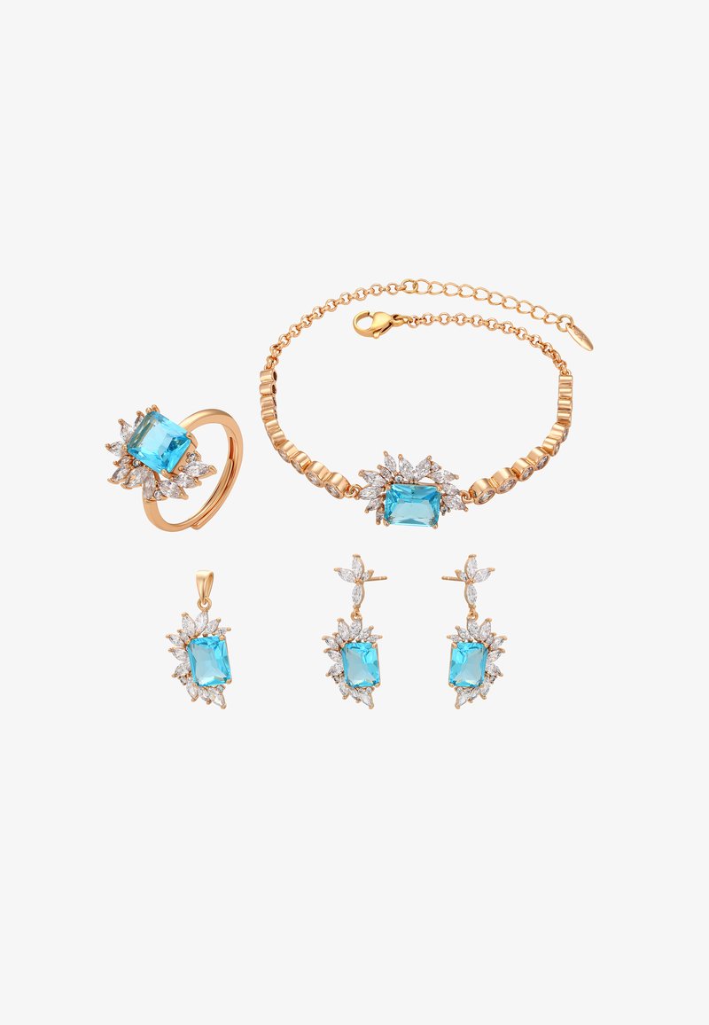 Un set di gioielli in oro composto da un anello, un bracciale, orecchini e un ciondolo. Ogni pezzo presenta una pietra blu centrale circondata da piccole pietre trasparenti.
