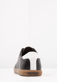 Černé kožené tenisky s bílou patou, textilními tkaničkami a gumovou podrážkou. Na patě mají decentní logo a texturované boky.