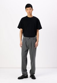 Black short-sleeve t-shirt paired with gray pinstripe trousers, featuring a fitted waist and a flat front, complemented by black shoes.