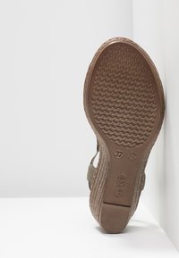 Semelle d'une sandale compensée marron montrant la semelle texturée, taille 37, et la marque Rieker sur fond blanc.