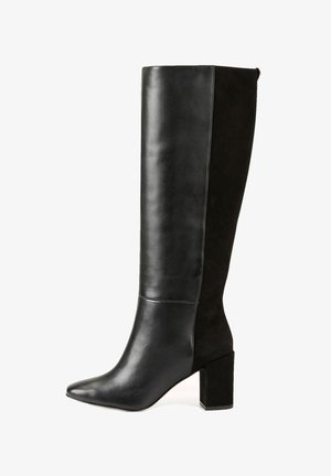 Botte montante noire pour femme avec un bout pointu, un talon bloc, et un mélange de cuir lisse à l'avant et de suède à l'arrière.