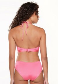 Un bikini rose avec un col halter et des liens, ainsi qu'une fermeture à clip au dos. Le tissu est lisse avec une coupe ajustée.