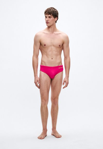 Φωτεινά ροζ μαγιό σλιπ με λεία υφή, ελαστική μέση και μικρό λογότυπο στολιστικό. Σχεδιασμένα για εφαρμοστή γραμμή.