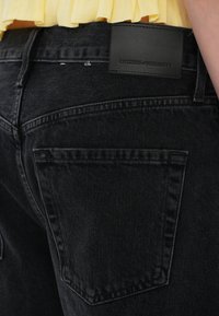 Jeans in denim nero con vita alta, dotati di una toppa in pelle etichettata "CITIZENS of HUMANITY" e tasche posteriori standard.