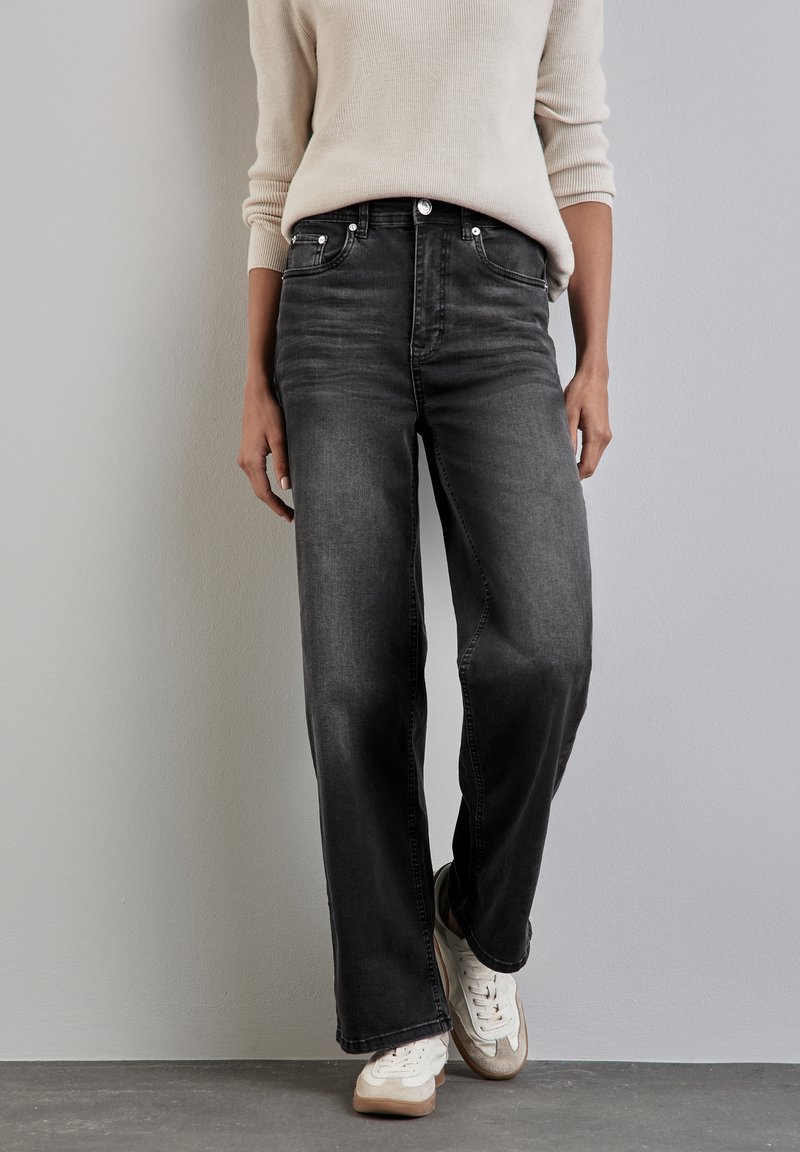 Zwarte wijde jeans met een vervaagde afwerking en een vijf-pocket ontwerp. Draag het met een beige trui en witte sneakers. Glad textuur.