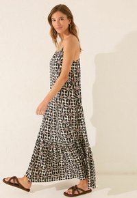 Abito maxi con un motivo geometrico bianco e nero arricchito da dettagli rossi, realizzato in tessuto leggero, con un orlo a volant a strati.