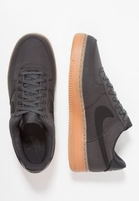 Šedé plátěné tenisky s černým logem Swoosh, texturovaným svrškem a podrážkou z gumové pryže. Šněrov ání a šití v odpovídající šedé barvě.